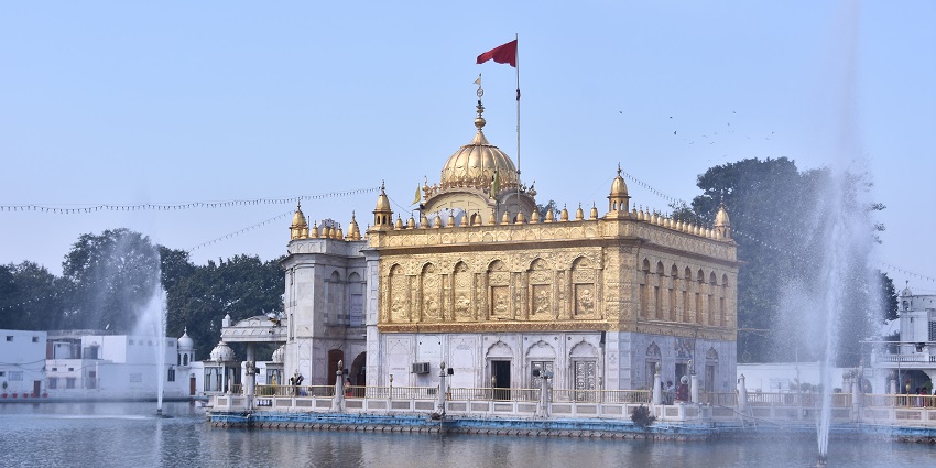 The Durgiana Temple adorned with white and golden hues and surrounded by azure waters.