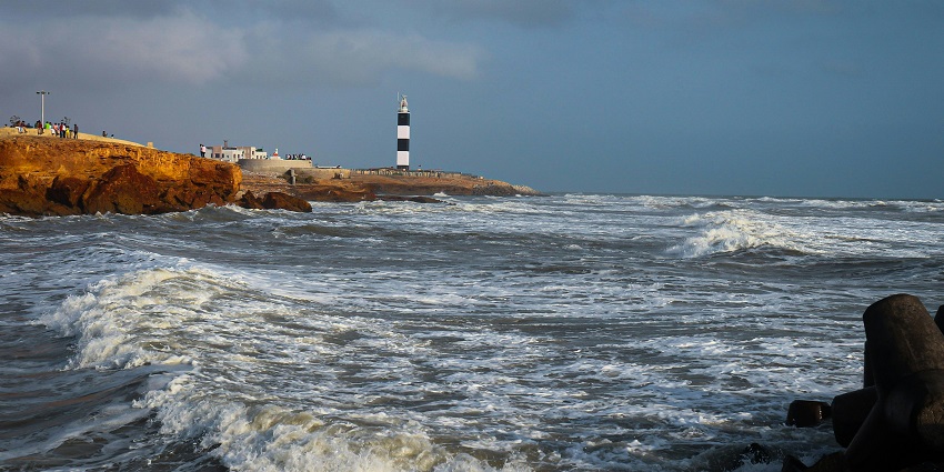 A mesmerising view of a water body in Dwarka with a lighthouse during the daytime.