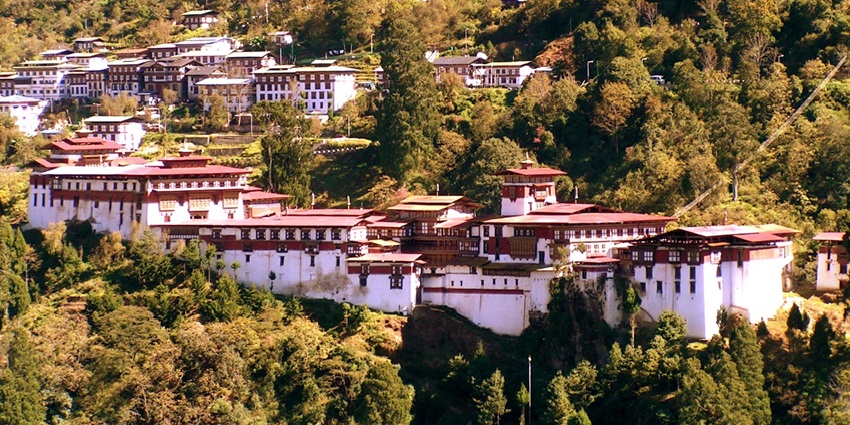 A distant view of the scenic Trongsa town in Bhutan, highlighting its unique placement amidst lush greenery
