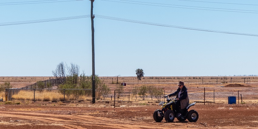 Image of a woman on Quad Biking near sand dunes surrounded by mountains during day time