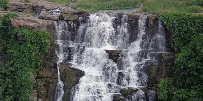 Scenic view if silver streams cascading down the moss covered rocks into the serene water pool