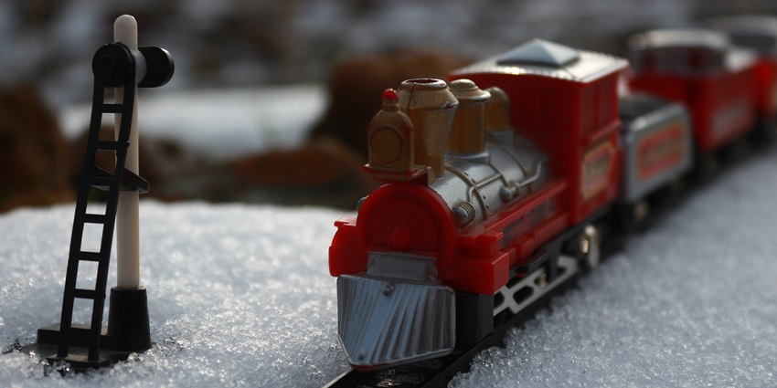 A train traveling through a snowy landscape under bright sunlight.