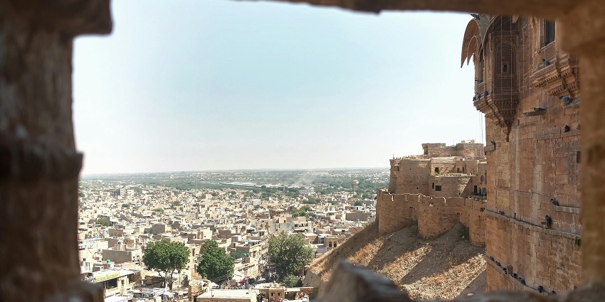 Ancient fortress overlooking an old city, with historic buildings in the background.