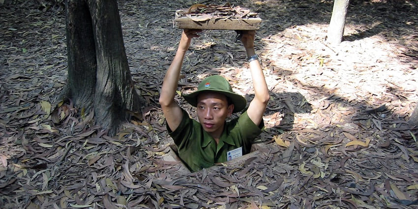 A man at the entrance to the Cu Chi Tunnels, showcasing Vietnam’s wartime underground network