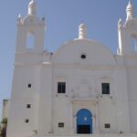 A shining white exterior view of St. Thomas Church with a museum on its premises.