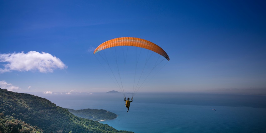 A person paragliding in Kufri through the valleys and observing the enchanting views.