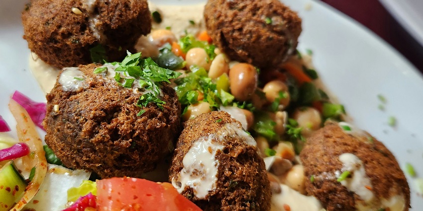 Plate served with delicious Falafel with Hummus sitting on a flat table for all to enjoy.