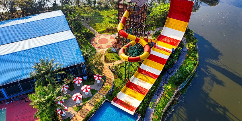 A serene view of colourful rides surrounded by lush green vegetation at Fantasy Lagoon.