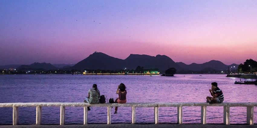 Visitors enjoying a beautiful sunset over the Fateh Sagar Lake under a pink sky