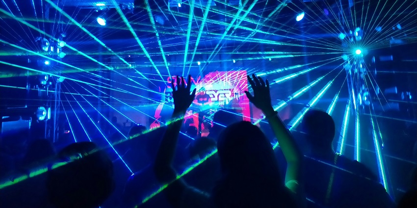 A view of the Feel Alive club decked with glistening neon lights and people dancing.