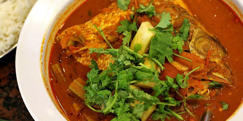 A savoury fish head curry served on a banana leaf, popular in Singaporean cuisine.