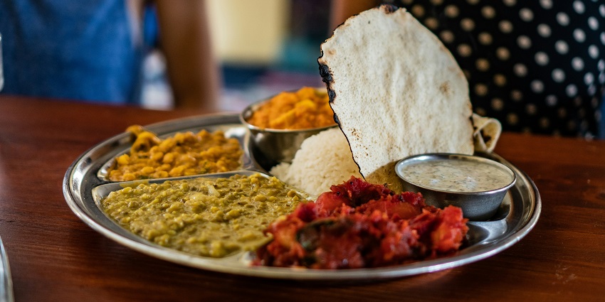 Flatbread placed next to a platter of steamed rice and stewed meat, showcasing a hearty meal.