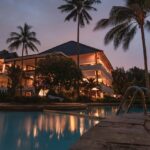 Palm trees illuminated at night, creating a serene tropical atmosphere during the nighttime, similar to the ambience in Forsyth Lodge, Satpura National Park.