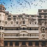 A glimpse of a majestic fort standing against a picturesque backdrop with flying birds.