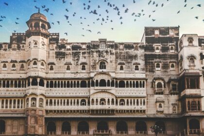 A glimpse of a majestic fort standing against a picturesque backdrop with flying birds.