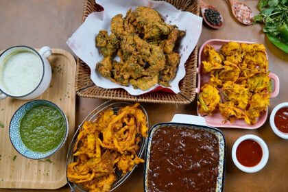 A glimpse of a variety of fritters being served with red and green chilli chutneys.