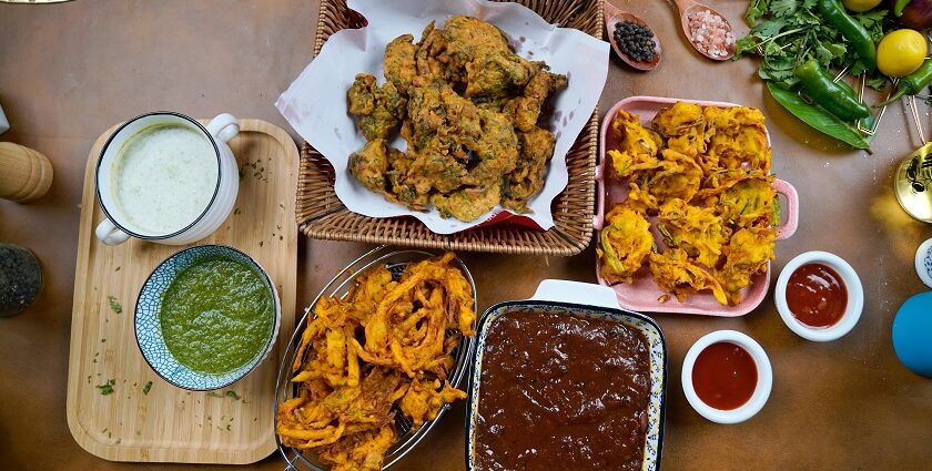 A glimpse of a variety of fritters being served with red and green chilli chutneys.