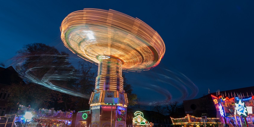 A picture of a tornado ride at a theme park in Delhi, taken during night time when the whole park is blinging