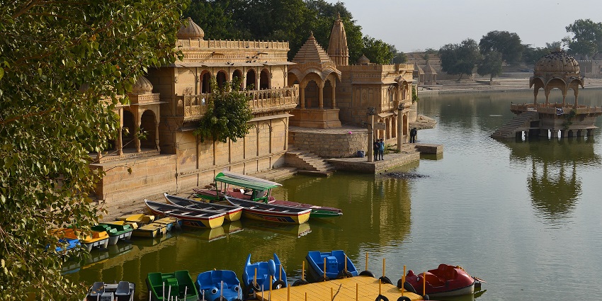 Buildings and a majestic fort border the Gadisar Lake.