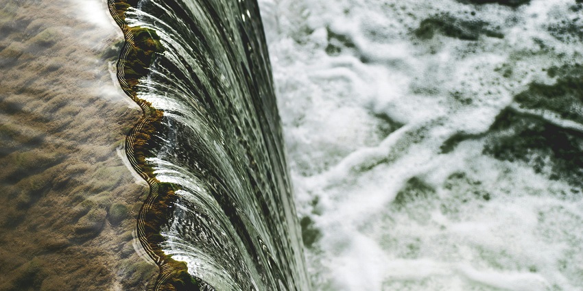 The photo of a large water stream and the surrounding rocks and water cascading.