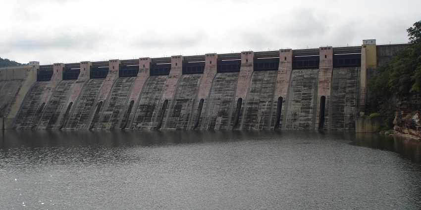 A wide-angle view of Gandhi Sagar Dam, a large concrete structure with water flowing through its spillways.