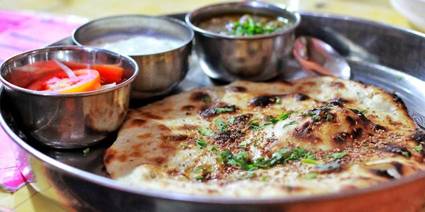 A picture of a plate of lentil stew served with crispy bread cooked in a clay oven