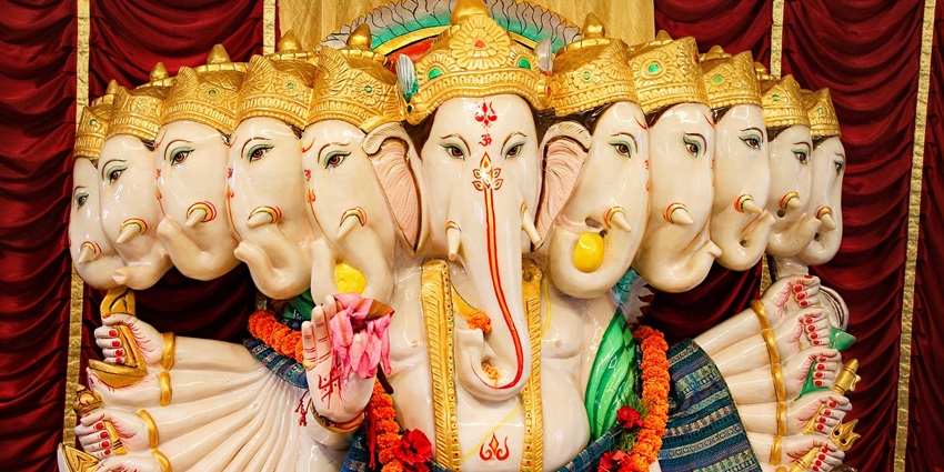 A picture of an Idol of lord Ganesh with a tree in the background on a beautiful sunny day