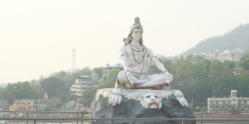 An image showing a close-up of a statue of Lord Shiva adorned with flowers and offerings.