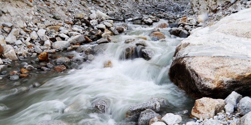 A tranquil waterfall cascading over rocks, surrounded by lush greenery.