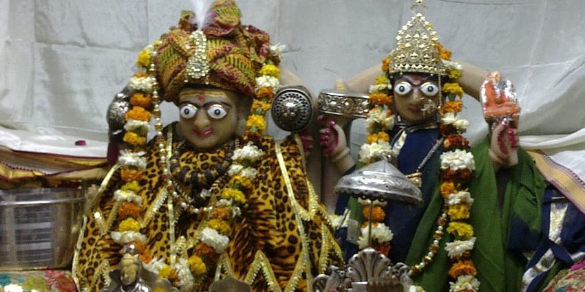 A picture of a temple with the idols of Lord Shiva and Goddess Parvati decorated in clothes and garlands