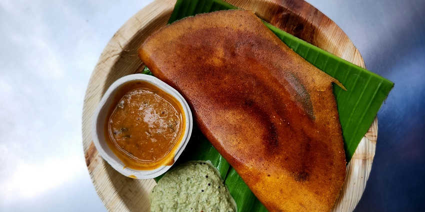 A golden-brown ghee roast dosa served on a plate, showcasing its crispy texture and rich flavour.