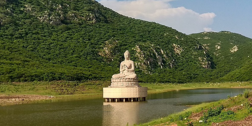 A picture of a lake near the Ajatshatru Fort with a Buddha statue around the shore