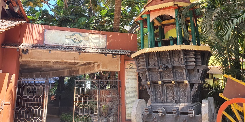 Image of the entrance Goa Chitra Museum surrounded by lush palm trees.