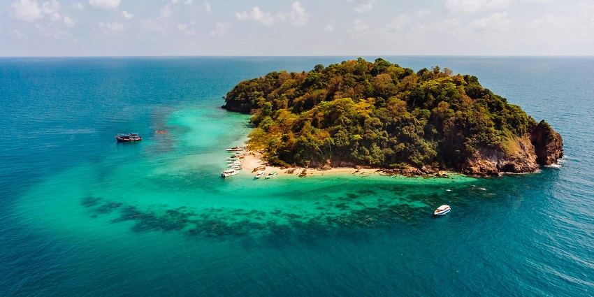 A bird’s eye view of the Grande Island surrounded by azure waters and decked with trees.