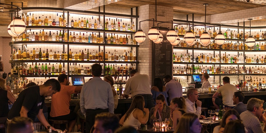 A lively group of friends enjoying drinks and conversation inside a cosy bar setting.