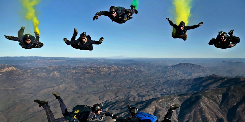 A group of colourful parachuters gliding through a clear blue sky, showcasing their skills.