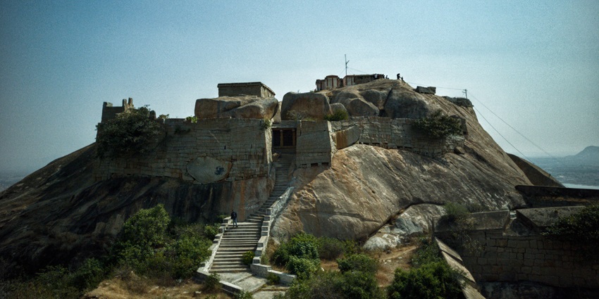 Stone-walled Gudibande Fort perched atop rocky hill with rugged stair pathways.
