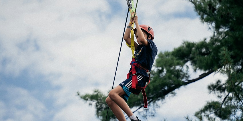 A stunning view of a child enjoying zip lining surrounded by lush greenery during the day.