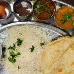 A glimpse of an array of dishes, rice, roti and a dessert being served on a plate.