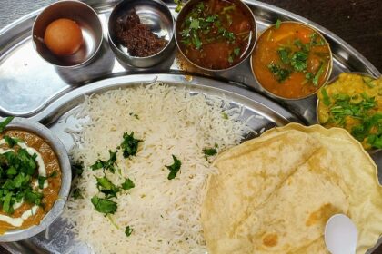 A glimpse of an array of dishes, rice, roti and a dessert being served on a plate.