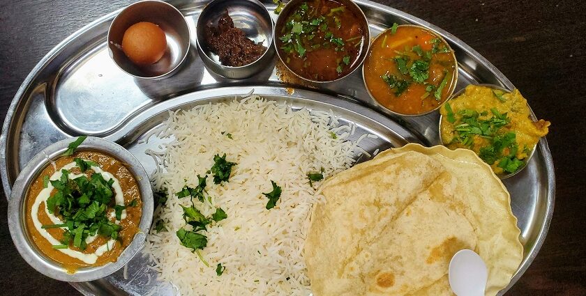 A glimpse of an array of dishes, rice, roti and a dessert being served on a plate.