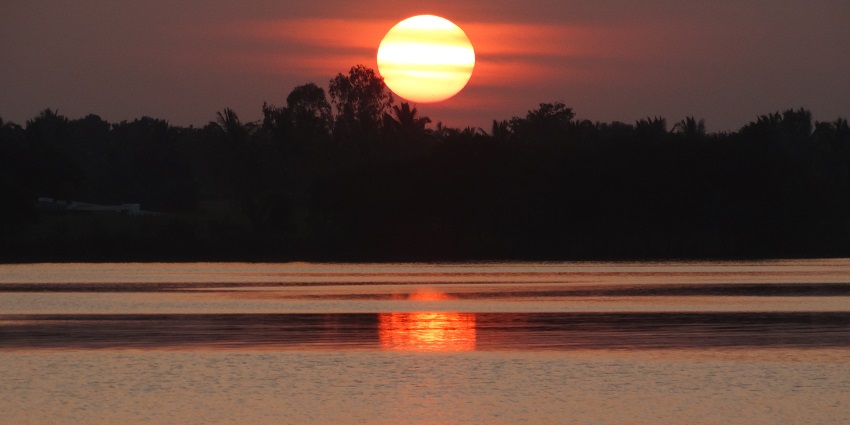 From the peaceful shore, a calm sunset throws warm colours across the lake.