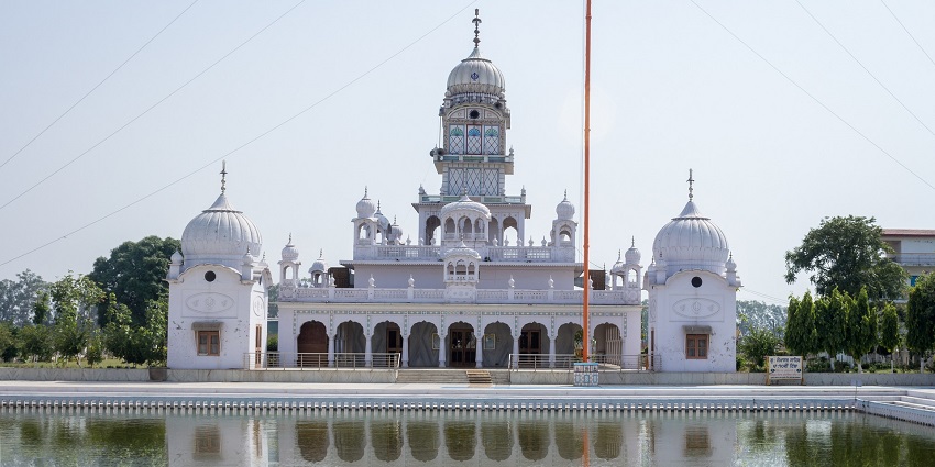 A picture of a gurudwara in Panchkula with a pond in the front