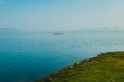 A glimpse of turquoise-blue waters of a lake meeting the lush green sprawling grounds.