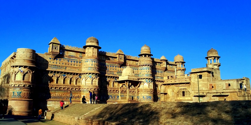 The Gwalior Fort, surrounded by greenery under a clear sky, is one of the top places to visit in Gwalior.