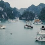 An aerial view of ships surrounded by cobalt blue waters and majestic peaks in Vietnam.