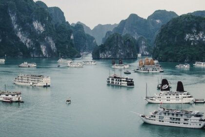 An aerial view of ships surrounded by cobalt blue waters and majestic peaks in Vietnam.