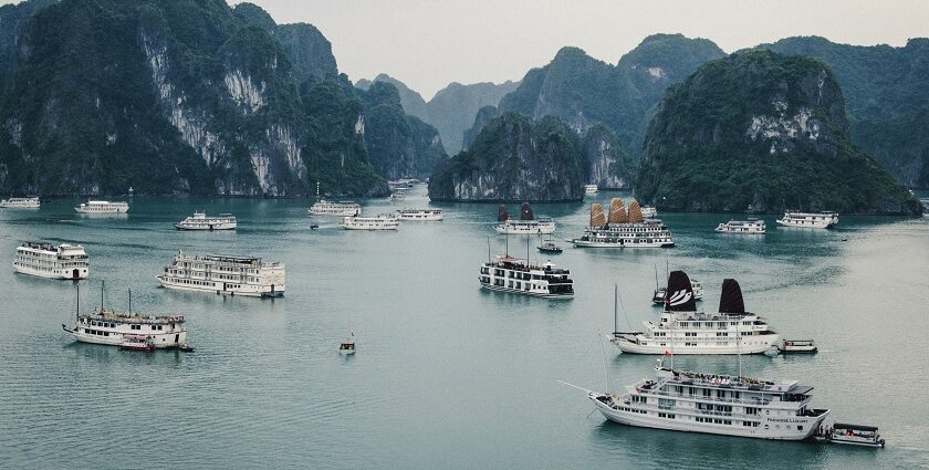 An aerial view of ships surrounded by cobalt blue waters and majestic peaks in Vietnam.