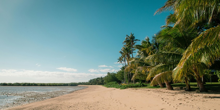 Empty serene beach with smooth sand meeting calm gentle-blue sea horizon–places to visit near vijayawada