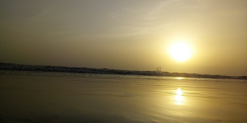 The bright setting sun reflecting on the water at Dandi beach, creating a mesmerizing view.